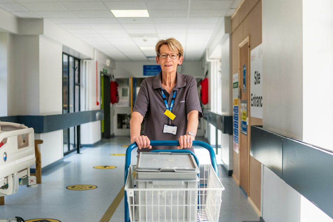 A staff member pushing a trolley down a bright facility corridor