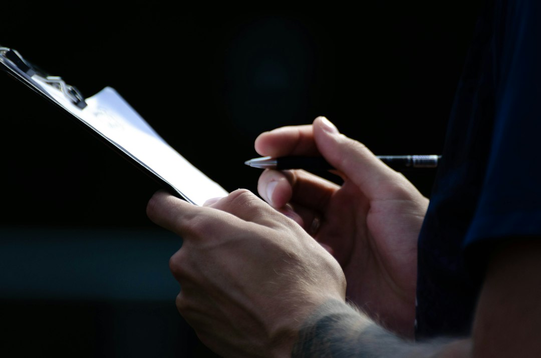 Hands writing on a clipboard in low light