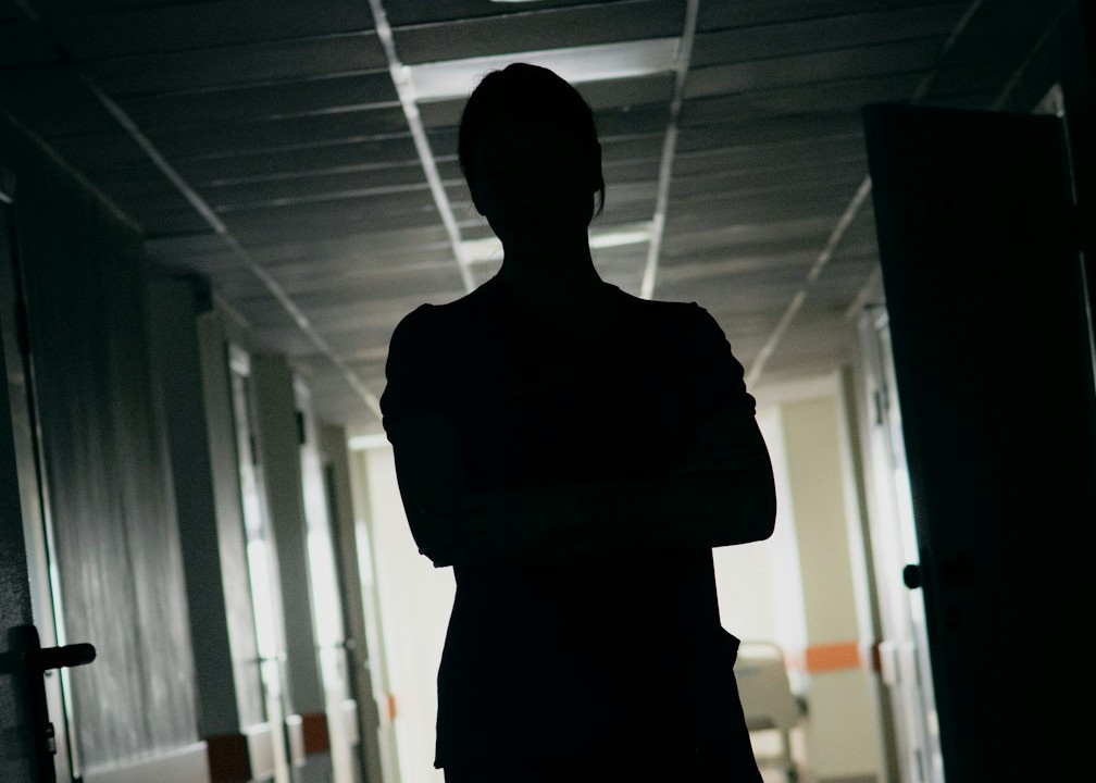 A lone figure standing watch in a dim hospital corridor